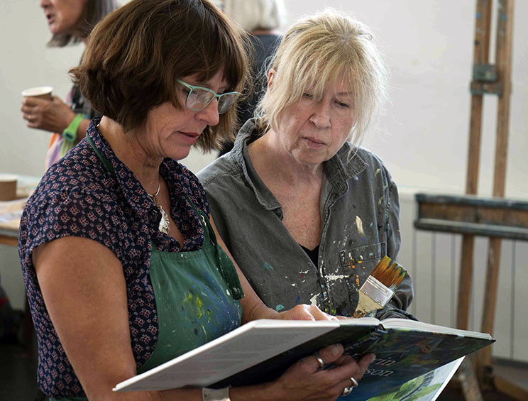Art Student looking at book with art teacher